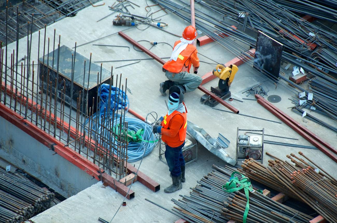 Site crew working among stacked reinforcement and building materials on a concrete deck.