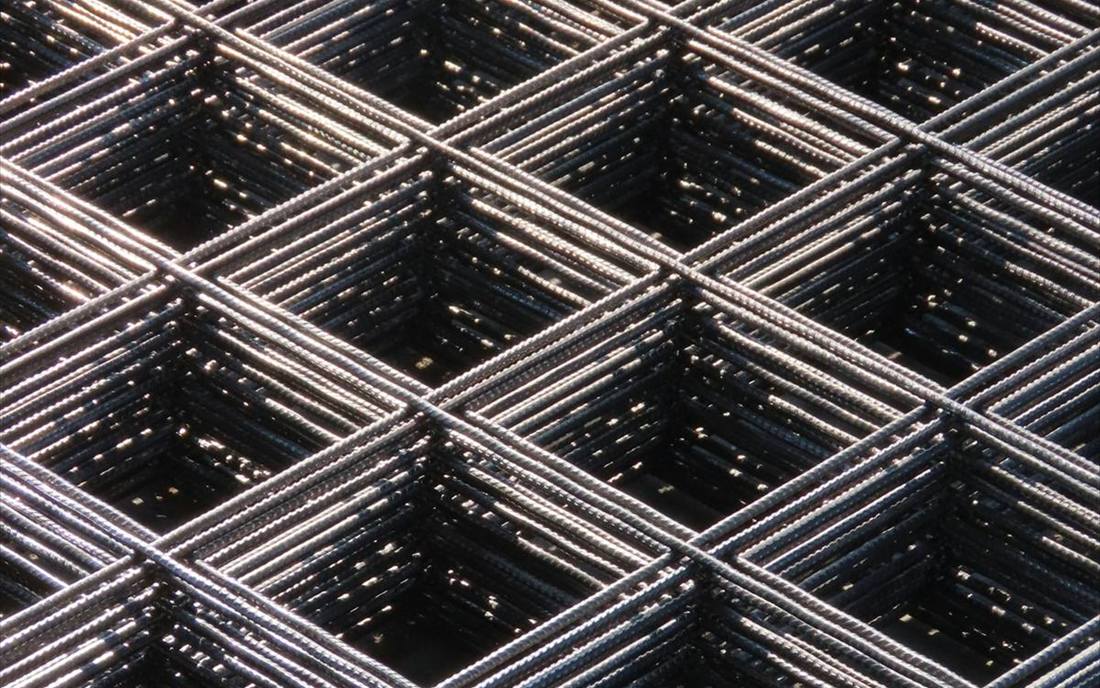 Sheets of reinforcing mesh stacked in a steel supply yard.