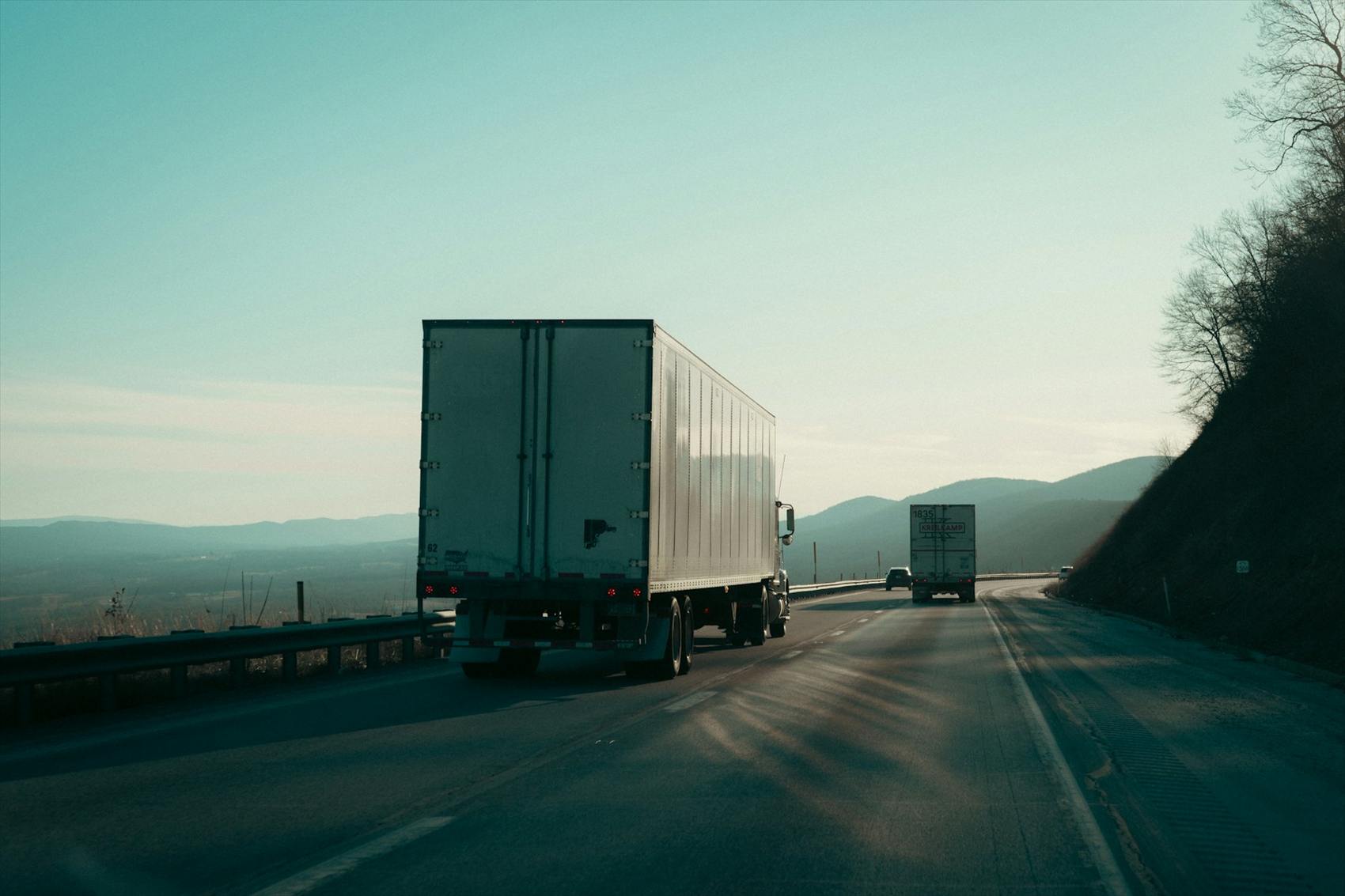 Freight trucks on an open highway at first light.